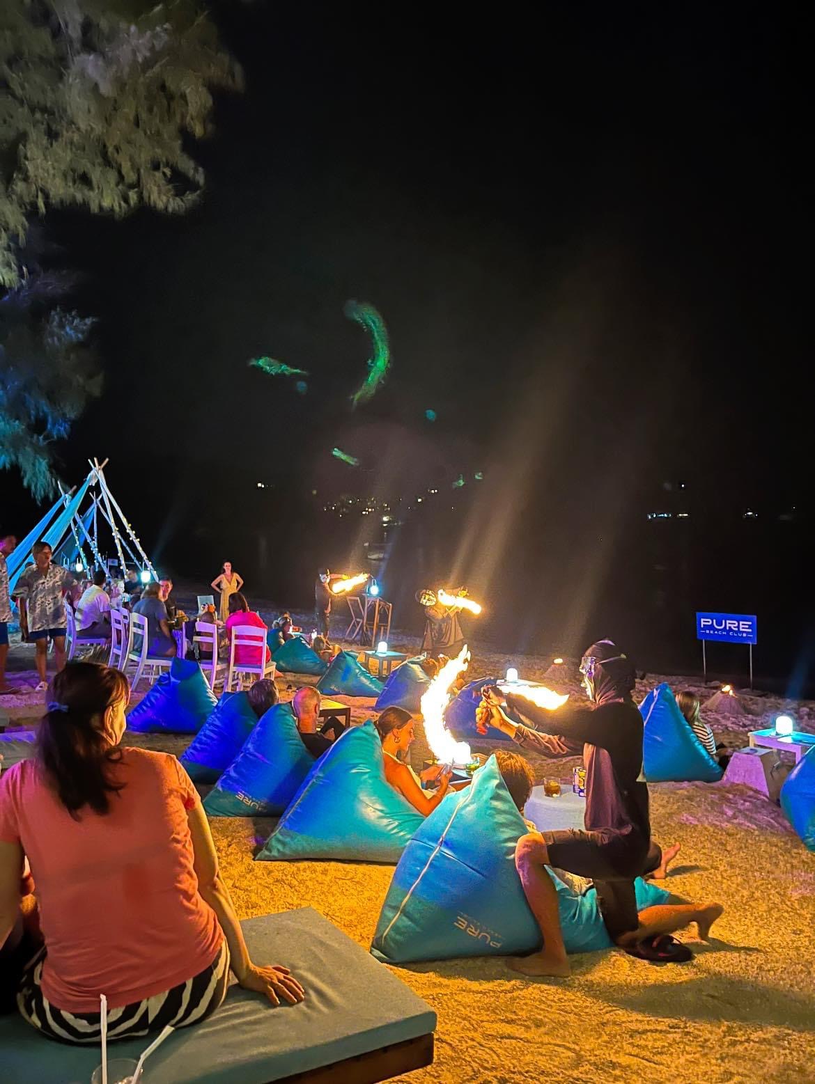Fire performer among the beachfront tables as the evening comes alive
