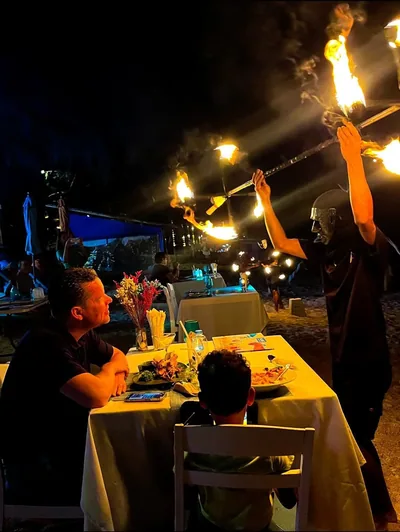Fire show performer at a dining table — guests watching at The Blue Spice, Choeng Mon Beach