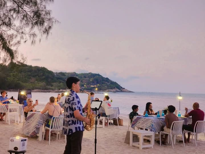 Saxophonist performing on the beach at dusk