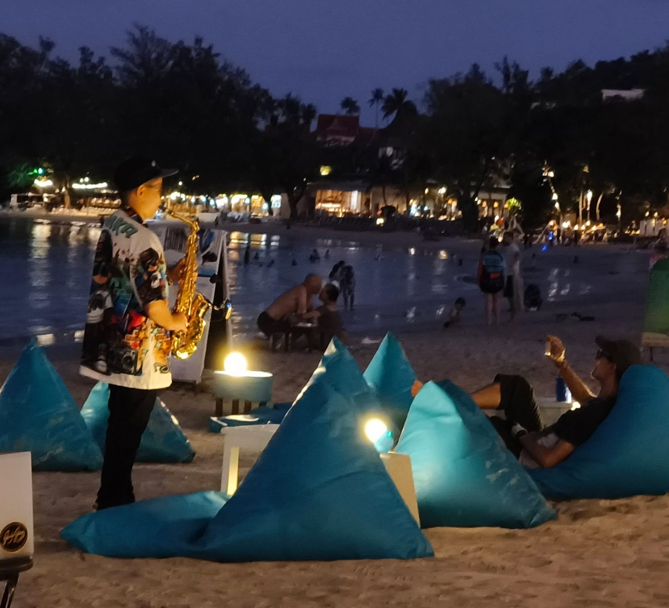Saxophonist performing among beanbags on the sand